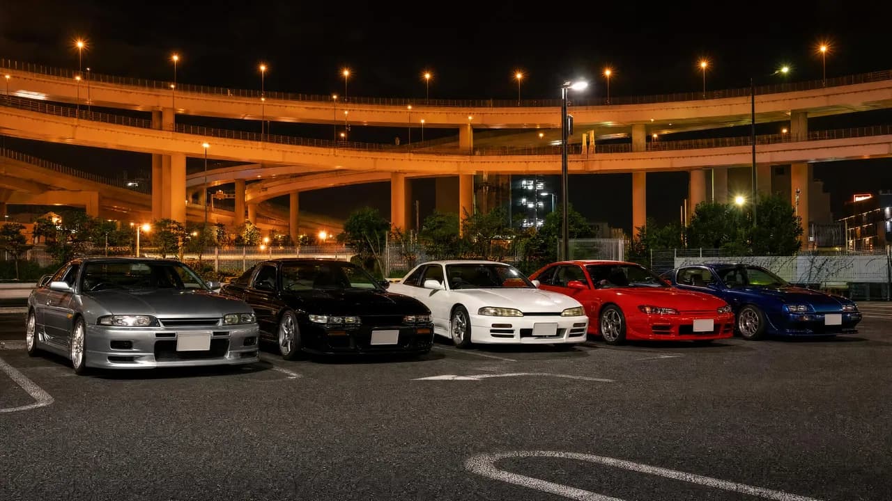 Classic JDM sports cars lined up at Daikoku parking area at night