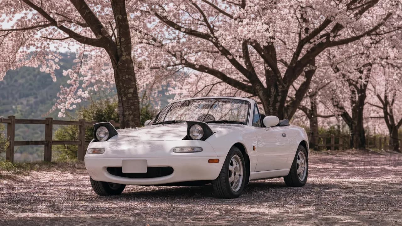 White Mazda Miata NA under cherry blossoms