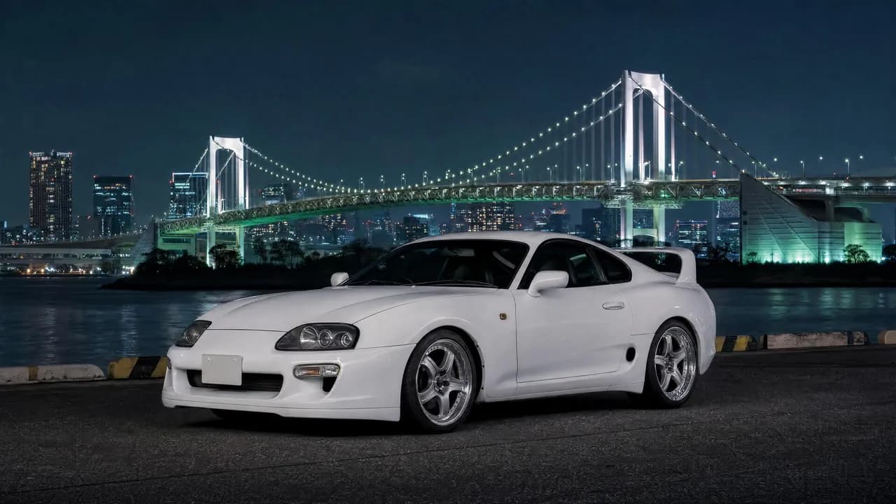 White Toyota Supra MK4 with Tokyo's Rainbow Bridge at night