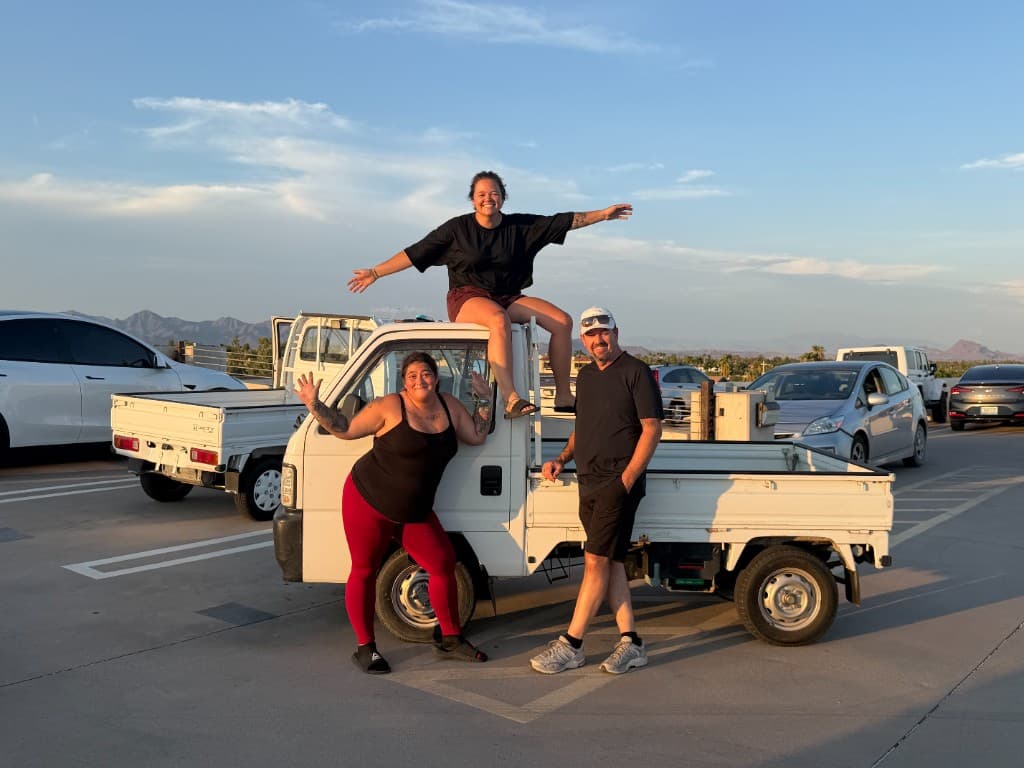 Cass and two friends posing with her white Honda Acty kei truck at sunset in Scottsdale, Arizona